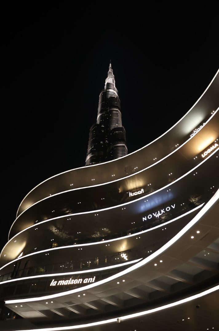 Night architectural photograph looking up a tower above a curved, illuminated building